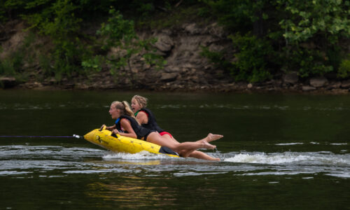 Kids on tube being pulled by a boat