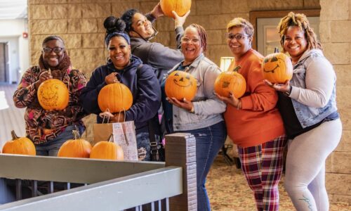 group of friends holding decorated pumpkins