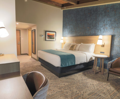 A guest room with a king bed. The wall behind the bed is deep blue with a gold flake pattern.