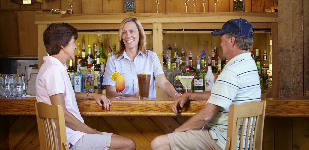 Bar with bartender and a couple ordering drinks