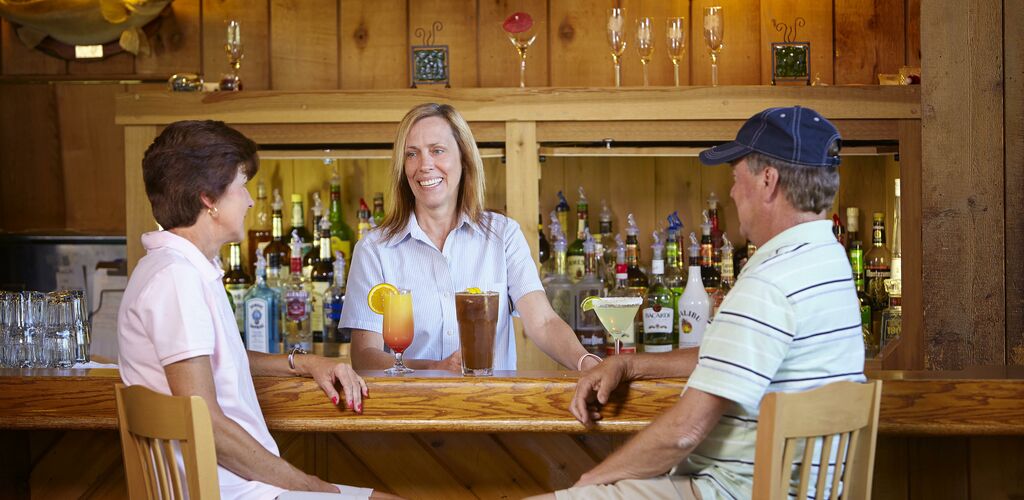 Bar with bartender and a couple ordering drinks